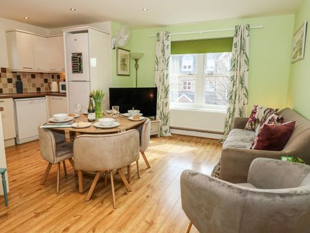 A living room with a dining table and kitchen appliances at Rodwell Holt in Weymouth