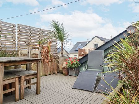 A patio with a table, chairs, and plants at Cove Retreat in Penzance