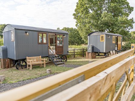 Two shepherd's huts with steps and a bench in a garden at No 1 The Orchard, Upton Warren