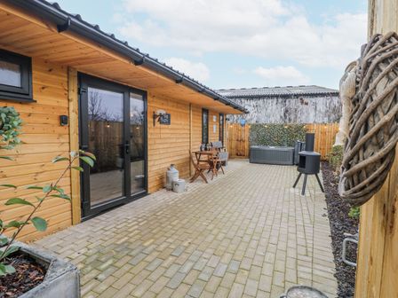 An outdoor area with a wooden cabin and patio furniture at The Sty in Hatton, Derbyshire