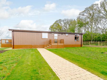 A wooden cabin with a pathway and grass at The Wansford in Kings Cliffe