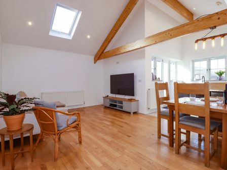 A living room with a sofa, table, and television at The Maisonette Hayle