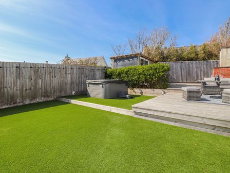 A garden with artificial grass and a hot tub at Bigting in Rhosneigr