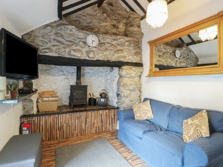 A living room with a fireplace and television at Fullers Studio in Caergeiliog