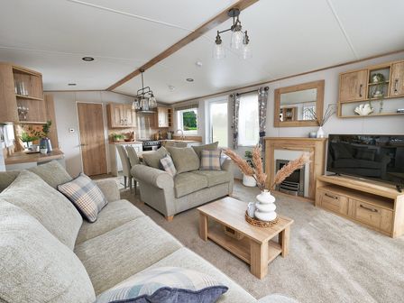 A living room with a sofa and television at Juniper Waterside Spa in Carlton Miniott near Thirsk