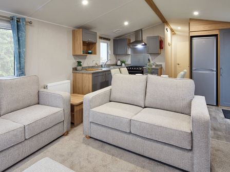 A living room with sofas and a kitchen area at Banyan Waterside Spa Carlton Miniott near Thirsk