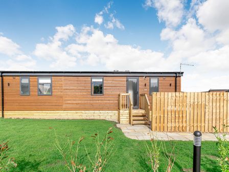 A wooden cabin with steps and a fence at Kinder Spa Carlton Miniott near Thirsk