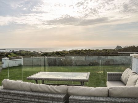 A sofa and coffee table on a terrace overlooking the sea at Dunholme