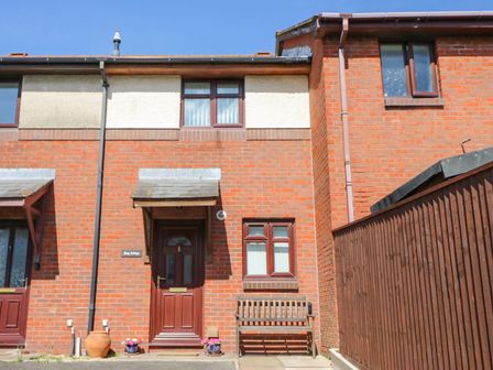 A house facade with a door and bench at Cozy Cottage in Poole