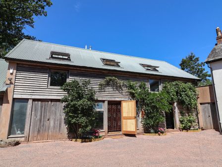 An exterior view of a building with wooden facade and plants at Captains Barn Tiverton