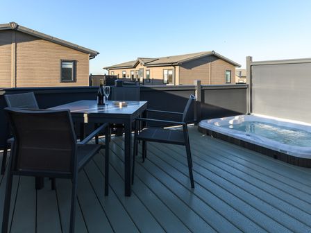 An outdoor deck with a table and hot tub at Grasmere in Penrith