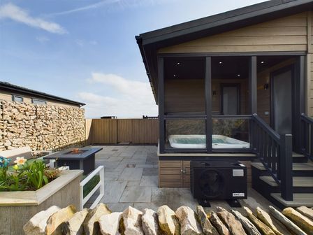 An outdoor area with a jacuzzi and flower bed at Spa Sauna Lodge (Pet) Penrith
