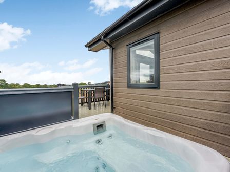 A hot tub on a deck beside a house at Helvellyn in Penrith