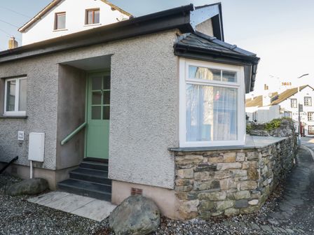 An exterior view of a house with a green door and stone wall at Renes Shop in Grange-Over-Sands