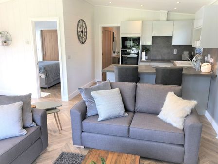 A living room with a sofa and kitchen area at Serendipity in Waltham