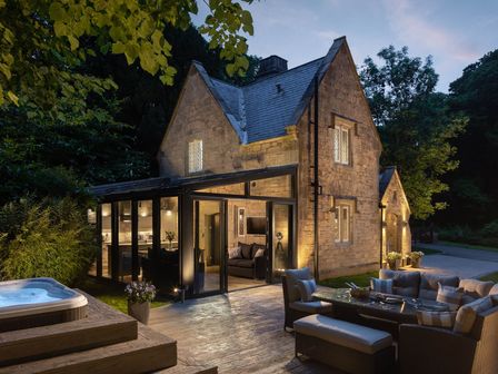 An outdoor seating area with a hot tub and a house at The Gatehouse in Praze-An-Beeble