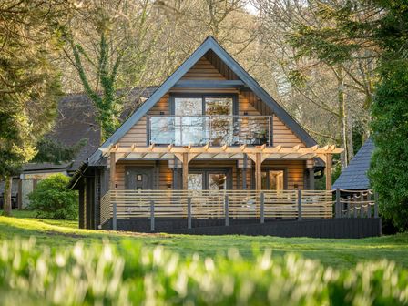 A house with a deck and windows at Lowarth Lodge Spa Pet Praze-An-Beeble