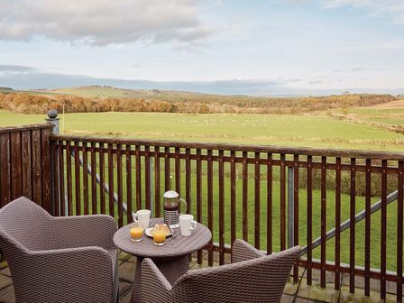 A balcony with a table and chairs overlooking a field at Duplex Apartment in Penrith