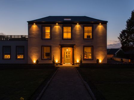 A house with lights illuminating the front entrance at The Farmhouse 1 Penrith