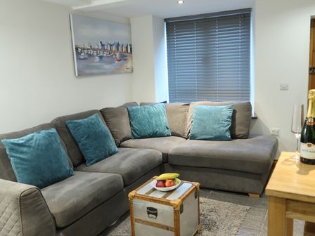 A living room with a sofa, table, and decorative items at Rockfish Cottage in Brixham