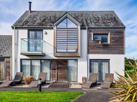 A house with a balcony and lounge chairs at Sheep's House in Marhamchurch