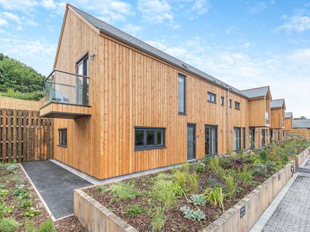 A wooden house with a balcony and garden at Gwari Spa Barn 3.0 in Marhamchurch