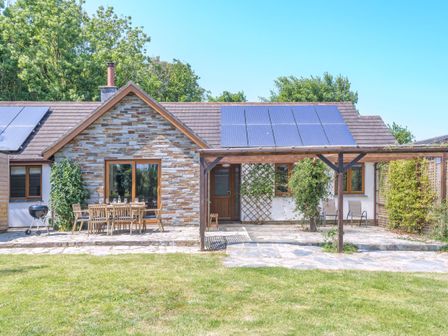 An outdoor view of a house with solar panels at Windy Hills Spa in Marhamchurch