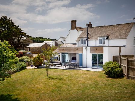 A house with outdoor seating area and garden at Whalesborough Cottage Spa in Marhamchurch