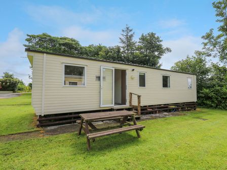A caravan with a wooden steps and picnic table at Caravan 3 at Blackmoor Farm near tenby