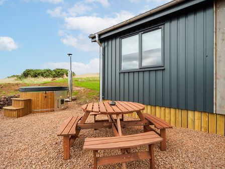 An outdoor area with a hot tub and a wooden table with benches at The Townsend in North Berwick