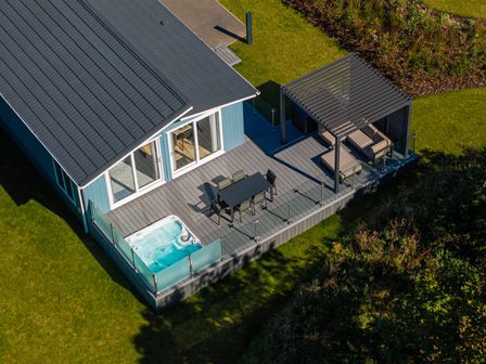 An outdoor area with a hot tub and dining table at Mullion 2 Spa, Bude