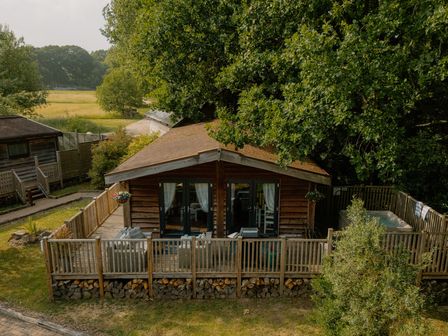 A log cabin with a deck and hot tub at Spitfire Lodge in Fair Oak