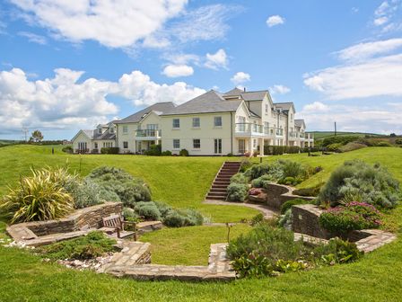 An outdoor area with a large house and landscaped garden at 8 Thurlestone Beach in Kingsbridge