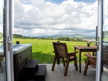 An outdoor seating area with a hot tub and table at Nethermill Lodges in Port Glasgow