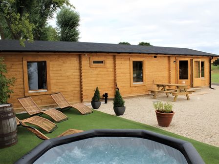 A log cabin with a hot tub and picnic bench at Cotswold Nights Away Evesham
