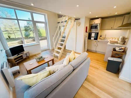 A living room with a sofa and staircase at Honey Bee Cottage Welshpool