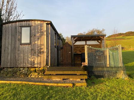 A wooden hut with a door and window at Shepherds hut Dumfries