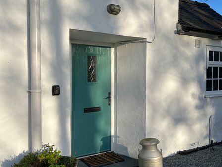 A blue door with a letterbox and light fixture at Bodior Garden Cottage Bach Rhoscolyn