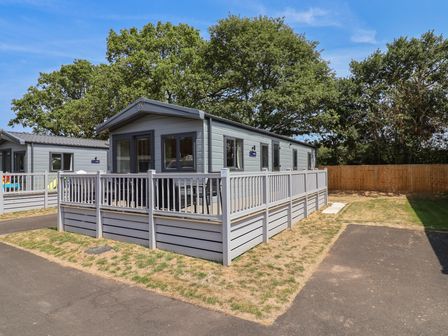 A cabin with a deck and a fenced area at The Oaks 3 Bedrooms Delamere