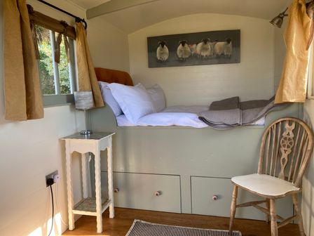 A bedroom with a bed and chair at Cosy Shepherd’s Hut Longhope