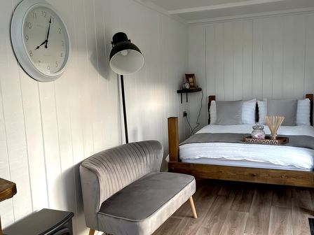 A bedroom with a bed and a seating area at Trethowels Hidden Huts in St. Austell