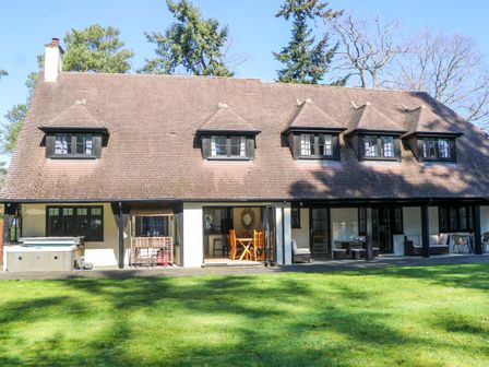 A house with patio furniture and a hot tub at Woodlands House in Ringwood