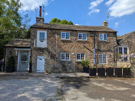 An outdoor view of a cottage with windows and a staircase at Bridge House Cottage Burn Bridge near Harrogate
