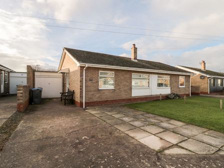 A bungalow with a driveway and garage at Megstone Chathill