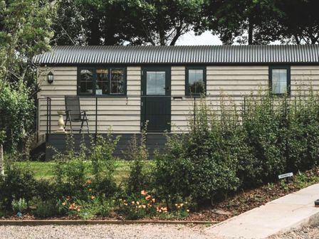 A cabin with a chair on the porch at The Lodge in Upton Warren
