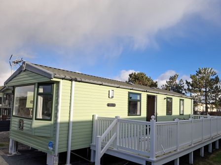A mobile home with a deck and trees at Caravan in