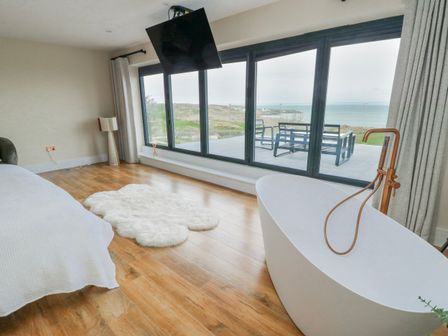 A bedroom with a bathtub and a view at Pengarnedd in Amlwch