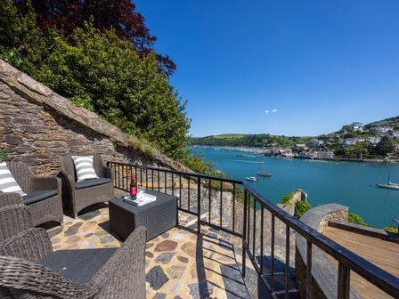 An outdoor seating area overlooking the water at Bell Cottage in Dartmouth