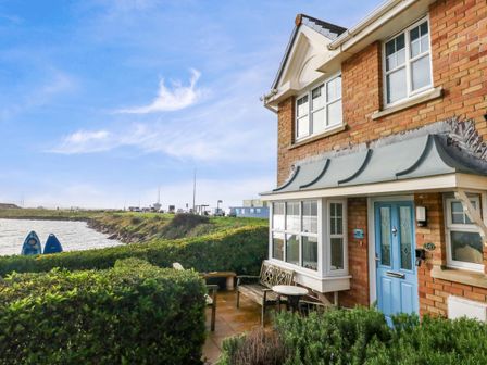 An outdoor area with a house and kayaks by the water at Still Waters in Weymouth