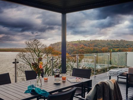 An outdoor area with a table and chairs overlooking a river at Wilde Spa (Pet) Carmarthen